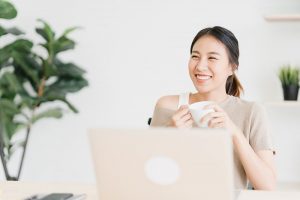 beautiful-young-smiling-asian-woman-working-laptop-drinking-coffee 800-min